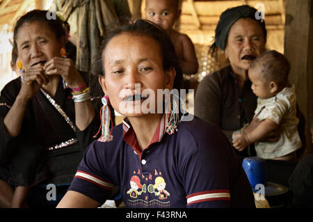 Ann women with black teeth and children inside a house in a village around Kengtung (Kyaingtong), Shan State, Myanmar Stock Photo