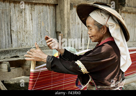 Aged Palaung woman with a conical hat weaving outside in a village around Kengtung (Kyaingtong), Shan State, Myanmar Stock Photo