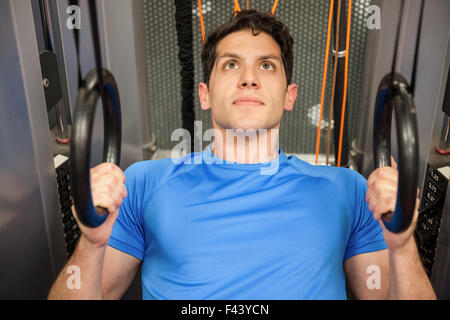 Man pulling himself up with the rings in hand Stock Photo
