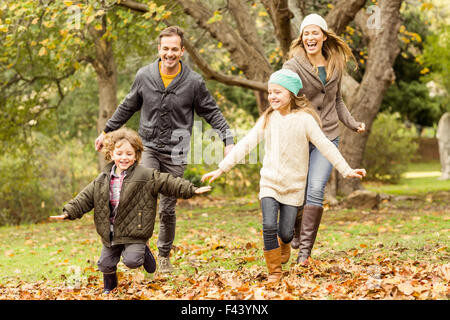 Smiling young family running into leaves Stock Photo