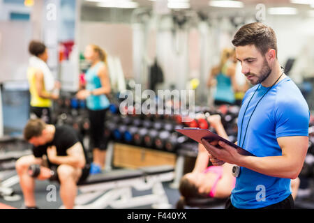 Handsome trainer looking at clipboard Stock Photo