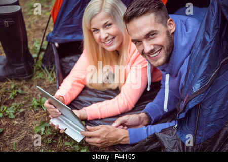 Happy couple lying in tent using tablet Stock Photo