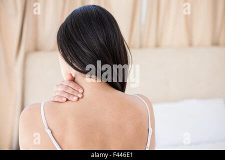 Pretty brunette with neck pain on bed Stock Photo