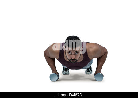 Muscular man doing push ups with dumbbells Stock Photo