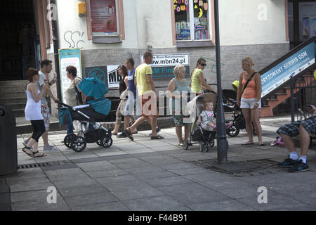 People stroll leisurely pushing baby strollers and eating ice cream in Zielona Gora, Poland during the summer. Stock Photo