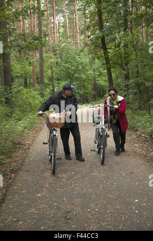 People walk their bicycles uphill in a forested area near Zielona Gora, Poland Stock Photo