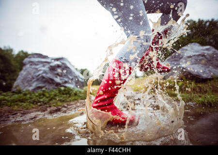 Woman splashing in muddy puddles Stock Photo