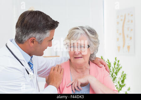 Doctor consoling senior patient in clinic Stock Photo