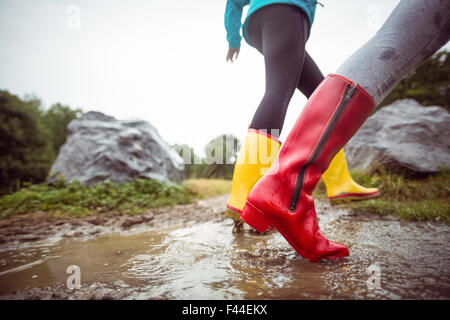 Women splashing in muddy puddles Stock Photo