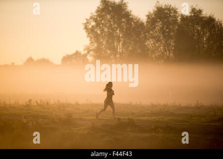 Female Cambridge University student  out training by the River Cam in Cambridge at sunrise on a misty morning. Stock Photo