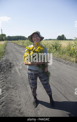Happy woman with freshly picked wild flowers on the road  in Central Poland. Stock Photo