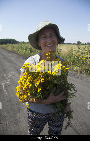 Happy woman with freshly picked wild flowers on the road  in Central Poland. Stock Photo