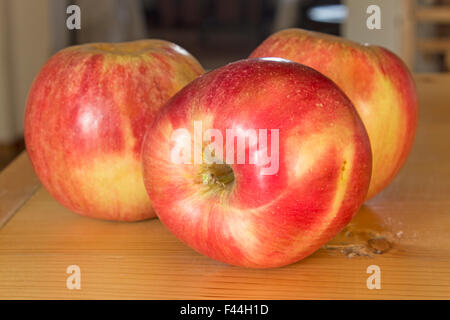 Three apples on the plank table. Stock Photo