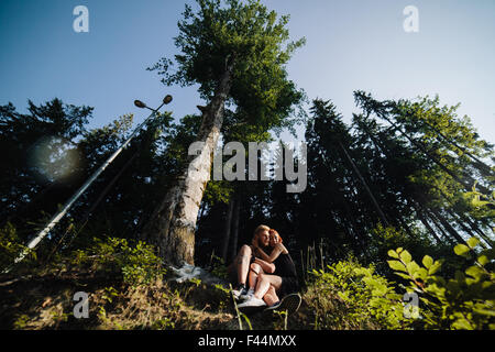 beautiful couple sitting in a forest near the tree Stock Photo