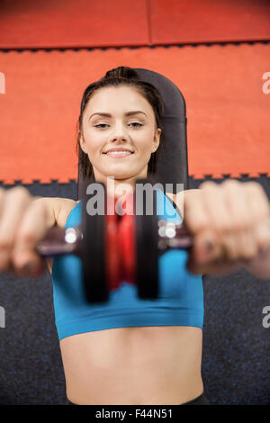 Focused woman lifting dumbbells while lying down Stock Photo