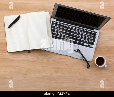 Laptop and opened Notepad on wooden table top view. Stock Photo