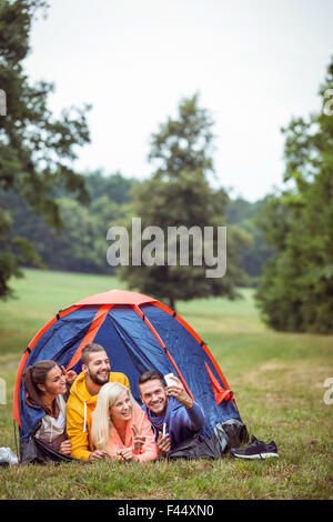 Happy friends lying in their tent taking selfie Stock Photo