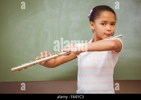 Little girl playing flute in classroom Stock Photo
