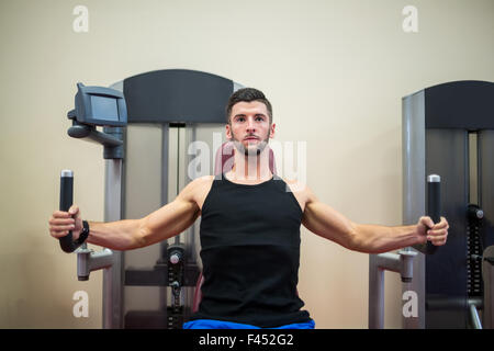 Focused man working out on the weights machine Stock Photo