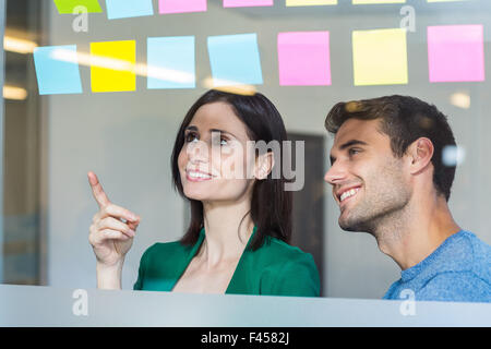 Smiling partners looking at sticky notes Stock Photo