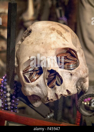 At the Voodoo Museum in New Orleans, the eye sockets of a human skull are filled with coins for good luck. Stock Photo