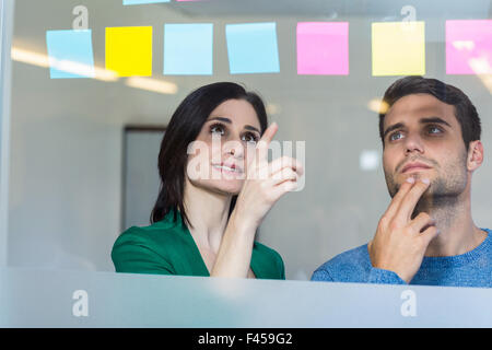 Smiling partners looking at sticky notes Stock Photo