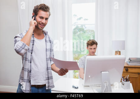 Man having phone call while his boyfriend working on computer Stock Photo