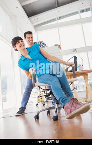 Smiling photo editors having fun with on a swivel chair Stock Photo