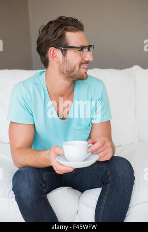 Happy handsome man sitting on couch with a cup of coffee Stock Photo