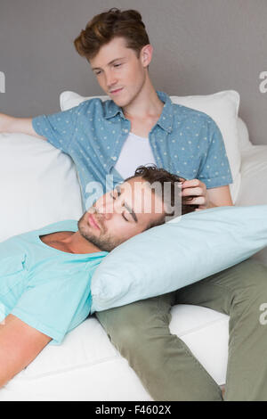 Handsome man sleeping on couch while his boyfriend is siting Stock Photo