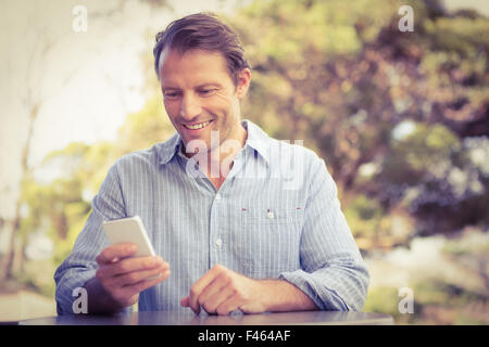 Smiling farmer using a smartphone while drinking a coffee Stock Photo