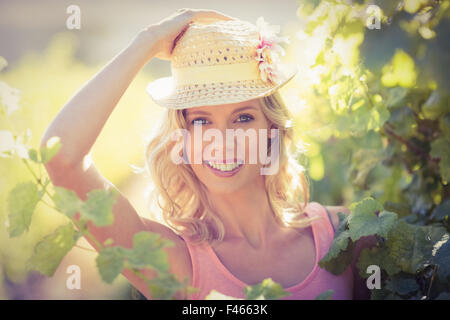 Portrait of smiling woman wearing straw hat and standing next to grapevine Stock Photo