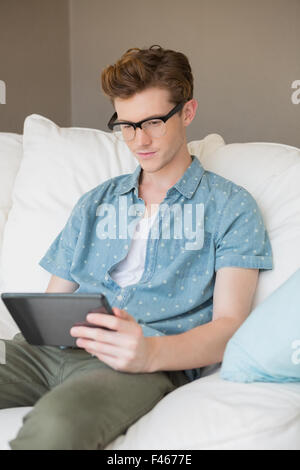 Concentrated young man using tablet on couch Stock Photo