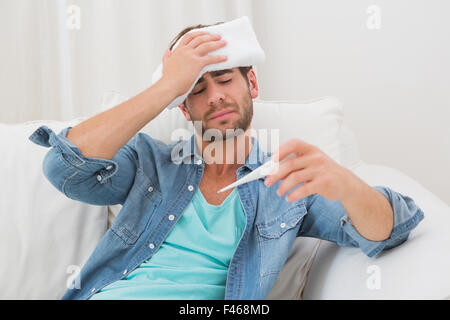 Sick handsome man sitting on sofa Stock Photo