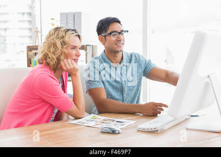 Smiling colleagues working on computer and pointing the screen Stock Photo