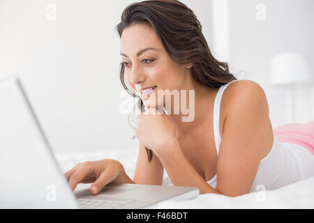 Smiling woman lying and using laptop Stock Photo