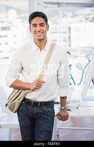 Young smiling businessman leaning against a desk Stock Photo