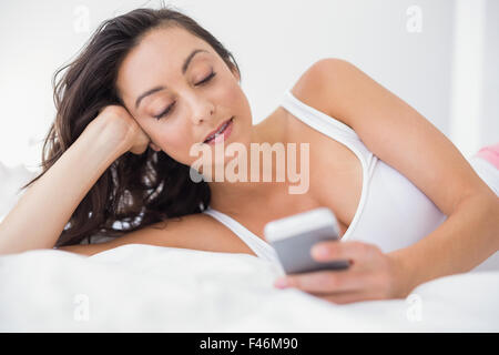 Smiling woman lying and using smartphone Stock Photo
