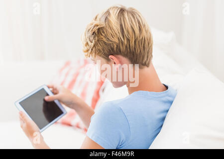 Rear view of woman sitting on couch and using tablet computer Stock Photo