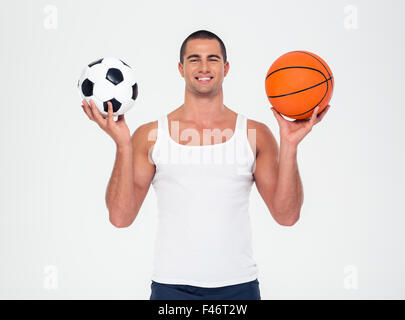 Portrait of a smiling man holding soccer and basketball ball isolated on a white background Stock Photo
