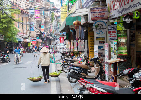 Hanoi old quarter with shops and stores, lady selling fruit from her yoke,Vietnam,Asia, typical street scene Vietnam Stock Photo