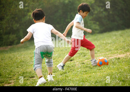 Two boys playing football in field Stock Photo