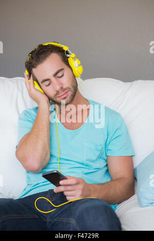 Relaxed handsome man listening music with headphones on couch Stock Photo