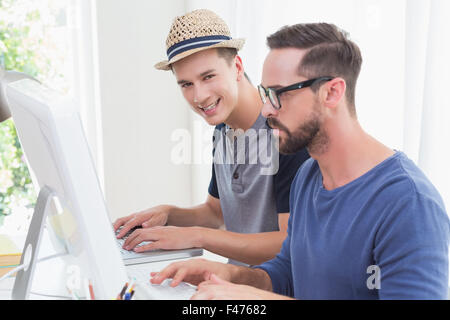 Happy handsome working on laptop with his colleagues behind Stock Photo