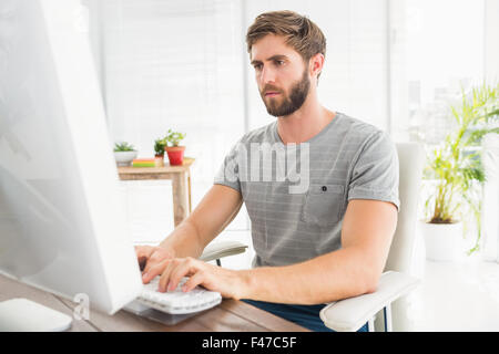 Handsome businessman sitting on a swivel chair and using his laptop Stock Photo
