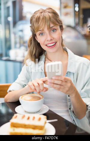 Beautiful woman holding mobile phone and smiling at the camera Stock Photo