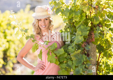 Portrait of smiling woman wearing straw hat and standing next to grapevine Stock Photo