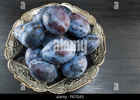 Plums in a bowl on a dark wooden table