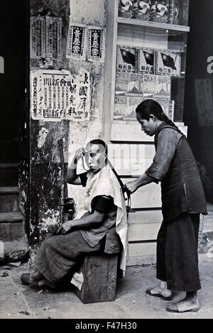 The cabinet behind the street beautician displays a brand of noodle named victory in 1946 following China's victory over Japan Museum of History, Hong Kong Chinese China Stock Photo