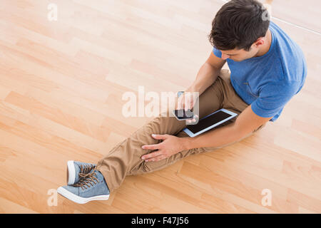 Businessman sitting on the floor using tablet Stock Photo